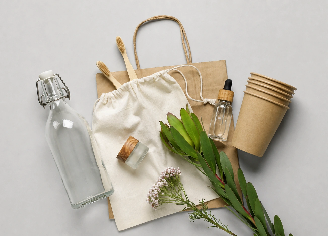 Nachhaltige Alltagsprodukte wie Stofftasche, Glasflasche, wiederverwendbare Becher und natürliche Pflegeprodukte.